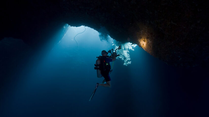Scuba divers inside underwater cavern By Lightning Strike Pro