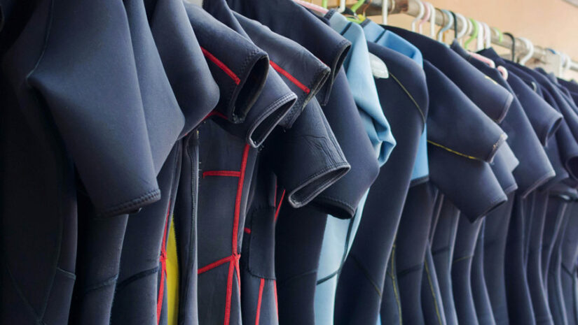 wetsuits hanging on a rack