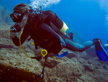 Scuba diver with bubbles. Diving in clear water wearing a dive computer.