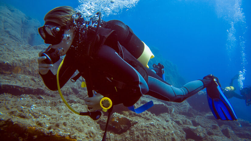 Scuba diver with bubbles. Diving in clear water wearing a dive computer.