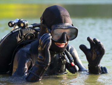 scuba diver emerging from water removing mask