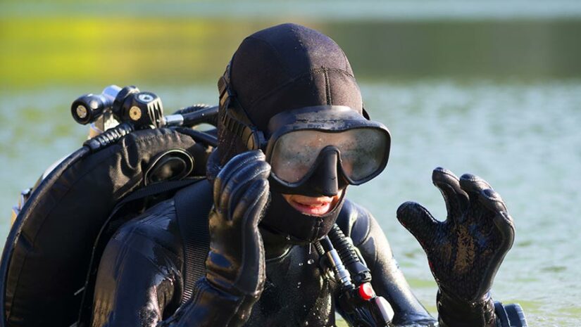 scuba diver emerging from water removing mask