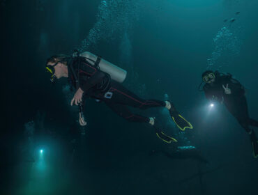 three divers using their flashlights in a cenote in mexico by Juanmarcos
