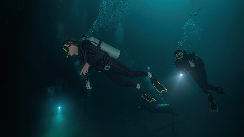 three divers using their flashlights in a cenote in mexico by Juanmarcos