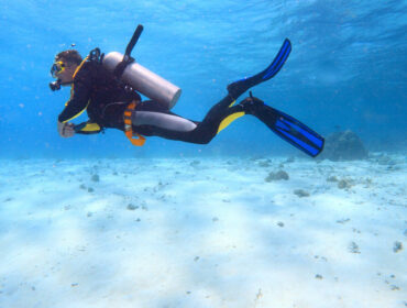 Scuba diver with fins swimming near the bottom of the ocean