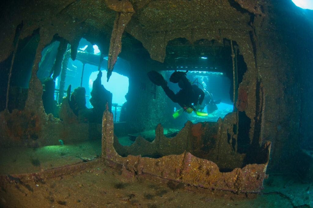 Scuba divers exploring a large shipwreck