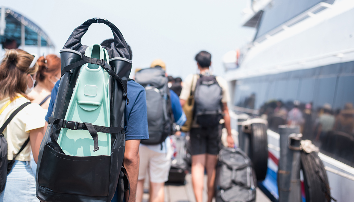 Traveler man with diving fins and travel bag walking the boat