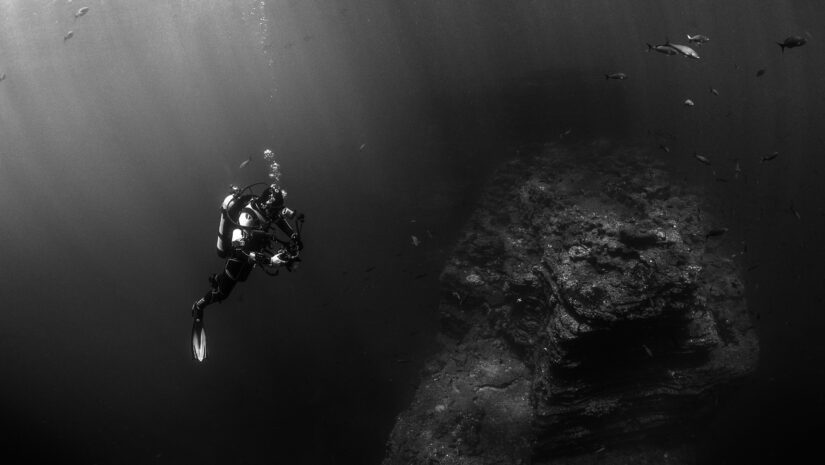 a diver looking at a huge rock formation