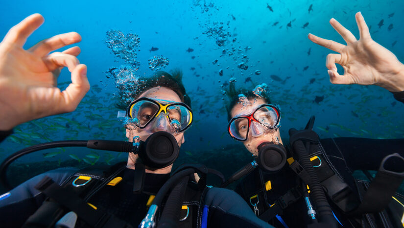 Couple of scuba divers showing ok sign, portrait photography By Jag_cz