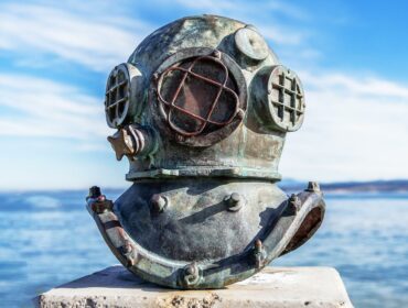 vintage scuba diving helmet displayed with the ocean in the background