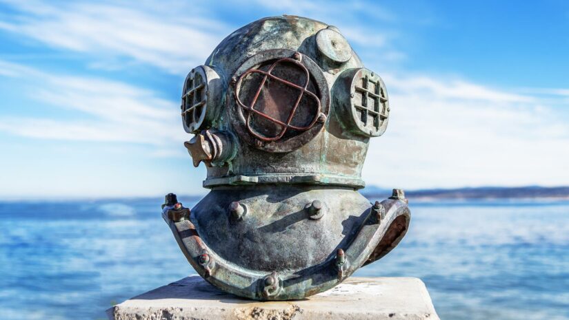 vintage scuba diving helmet displayed with the ocean in the background