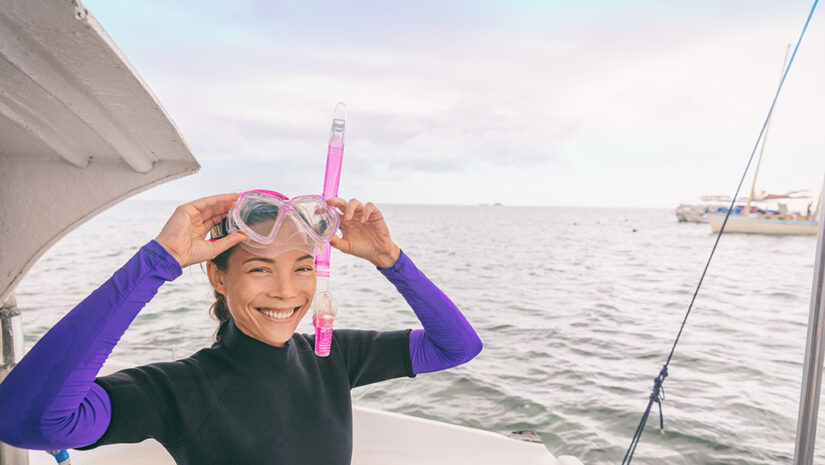 Snorkel watersport Asian woman tourist putting on mask for snorkeling activity in Miami, Florida, USA. Summer travel vacation.