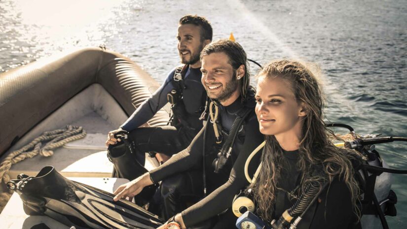 three scuba divers resting on a dive boat