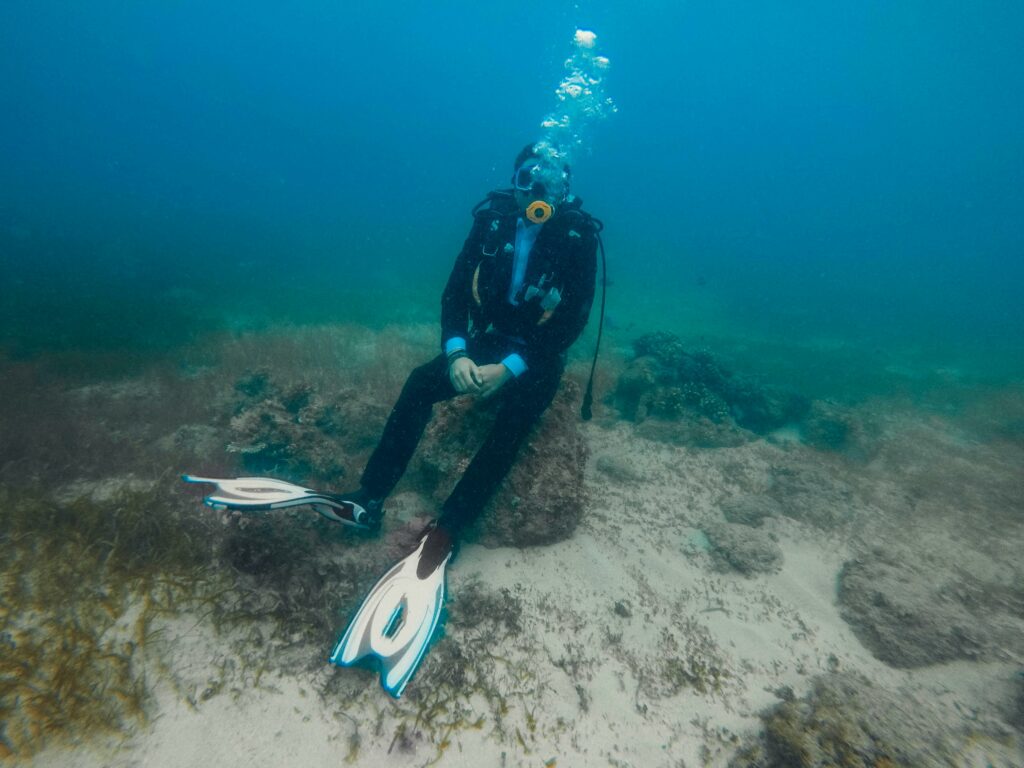 Dry suit diver sitting on rocks