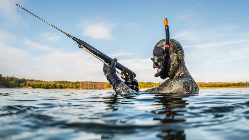 Spearfisher holding speargun above water