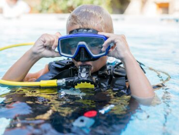 child on the surface of the water wearing scuba gear