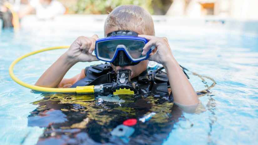 child on the surface of the water wearing scuba gear