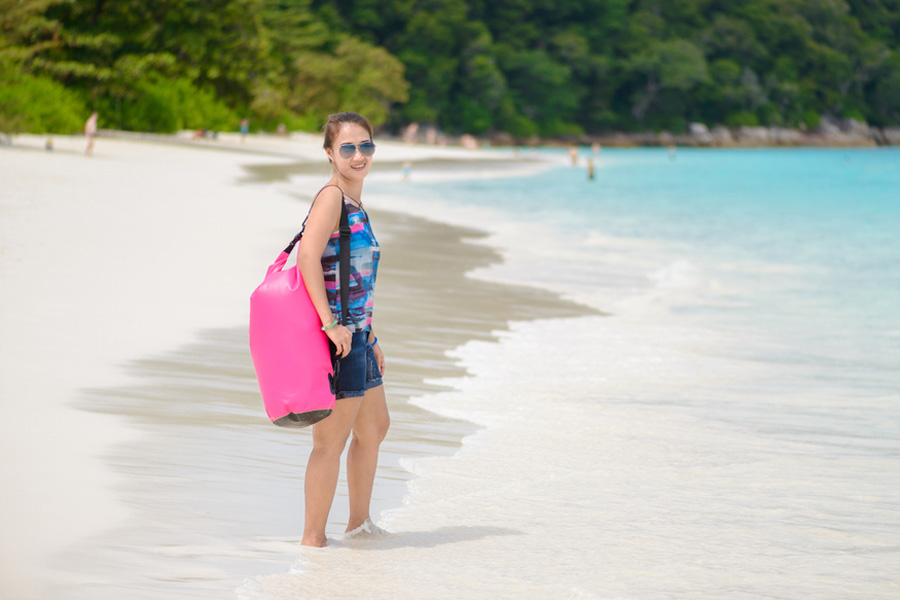 lady posing with pink dry bag by the shore
