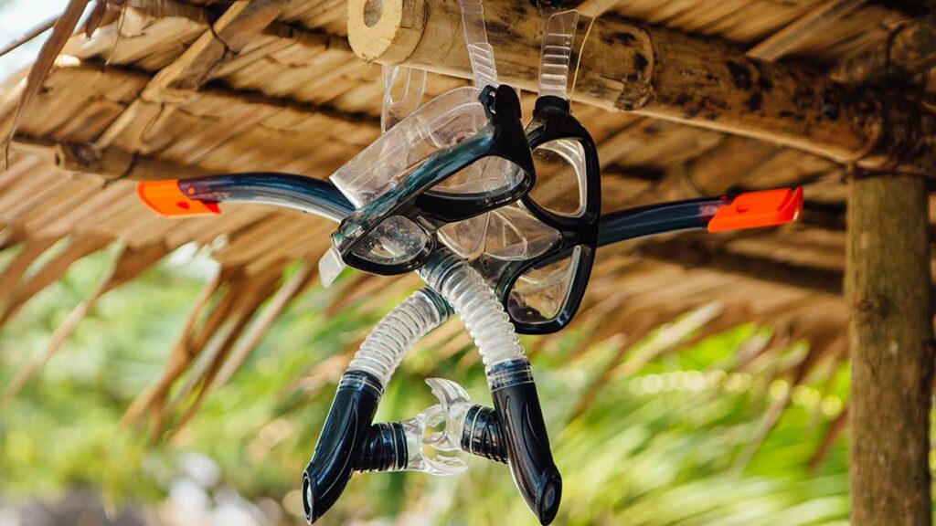 Two snorkeling mask are drying ander the wooden roof
