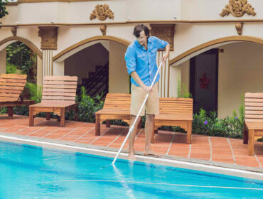 man cleaning an outdoor home pool