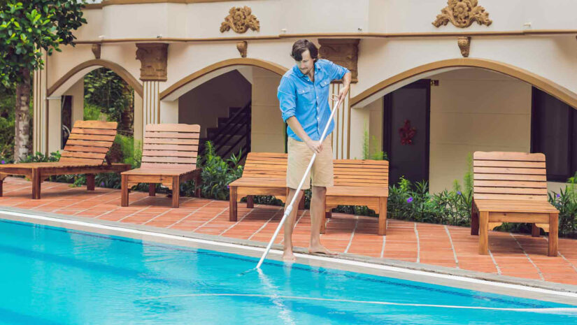 man cleaning an outdoor home pool