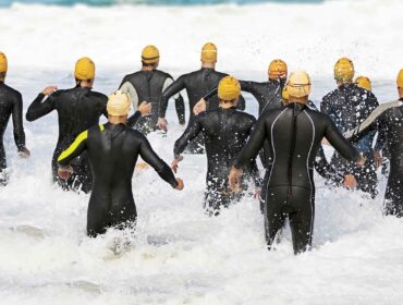 triathletes running towards the water for the first swimming leg