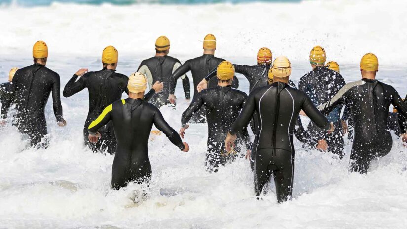 triathletes running towards the water for the first swimming leg