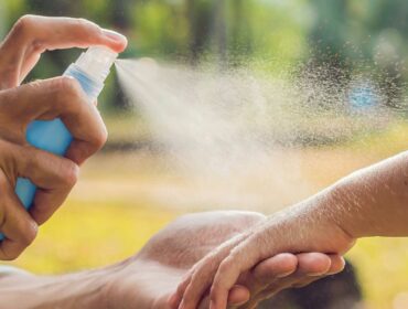 spraying insect repellent on a child’s arm