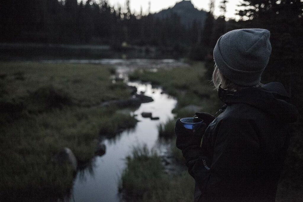 woman at creek water with cup in hand