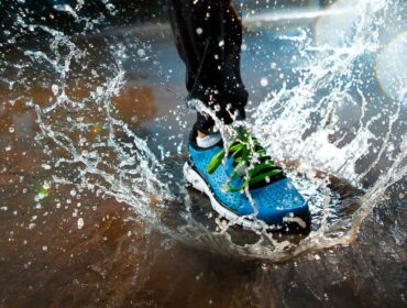 runner splashes through the rain and steps on a puddle