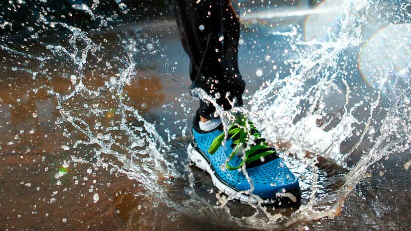 runner splashes through the rain and steps on a puddle