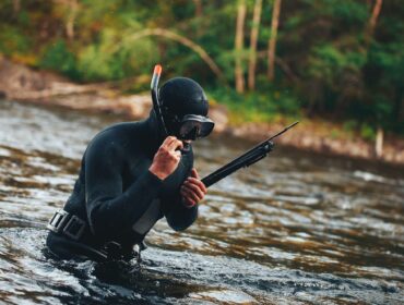 a hunter adjusts his mouthpiece above water after spearfishing