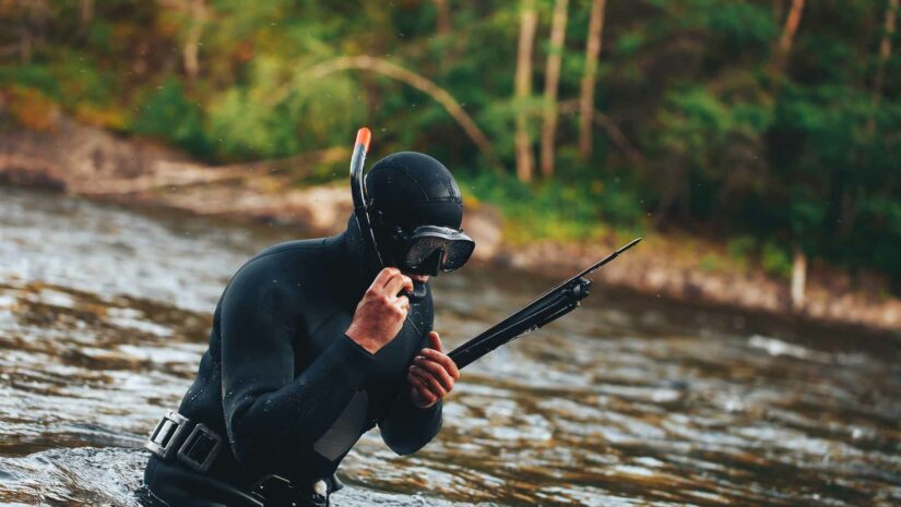 a hunter adjusts his mouthpiece above water after spearfishing