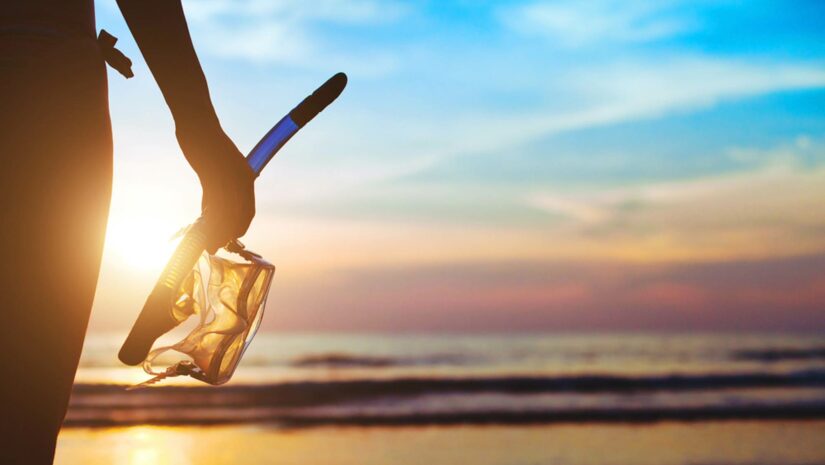 snorkeler looking over a sunset by the beach