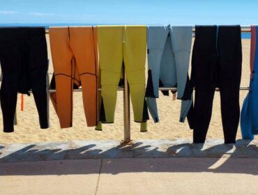 wetsuits drying on a metal rail
