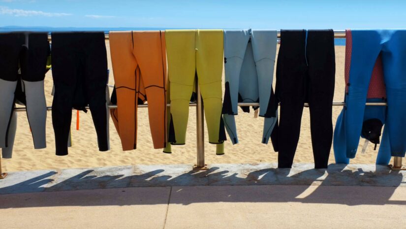 wetsuits drying on a metal rail