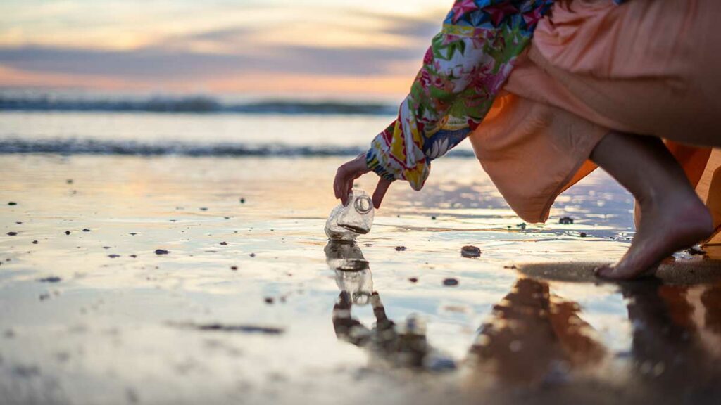 cleaning up plastic water bottle from beach