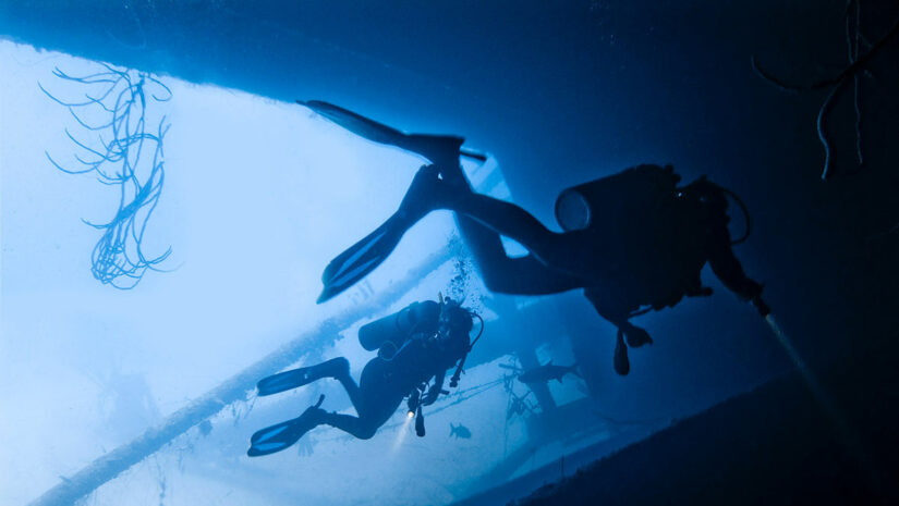 two scuba divers in dive wreck