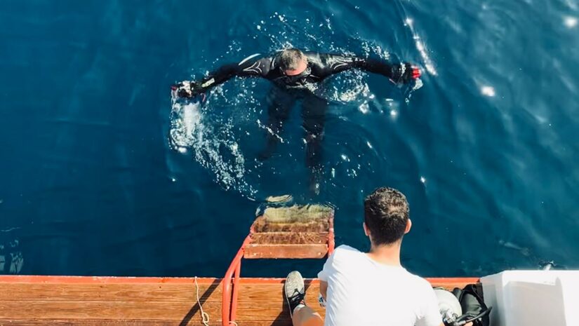 scuba diver surfacing next to boat