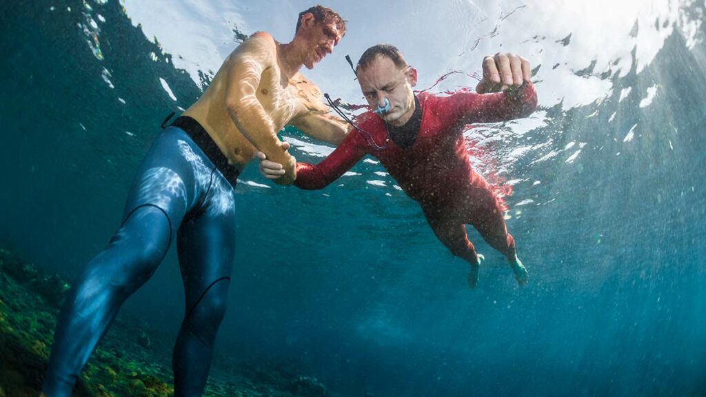 freediver using scuba diving nose clips to practice static breath hold with trainer in water