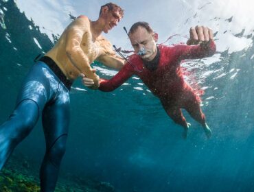 freediver using scuba diving nose clips to practice static breath hold with trainer in water