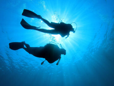 two divers underwater near surface of water