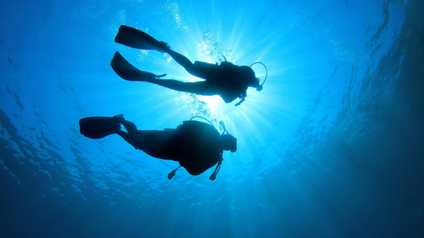 two divers underwater near surface of water