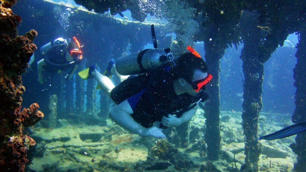 two scuba divers underwater shipwreck