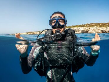 scuba diver surfacing above water wearing mask