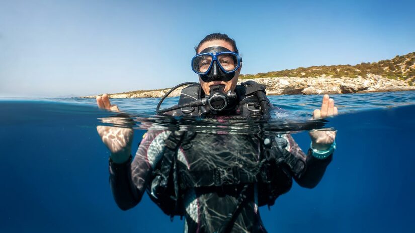 scuba diver surfacing above water wearing mask