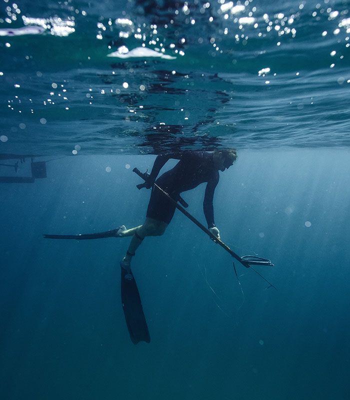 spearfisher with speargun underwater