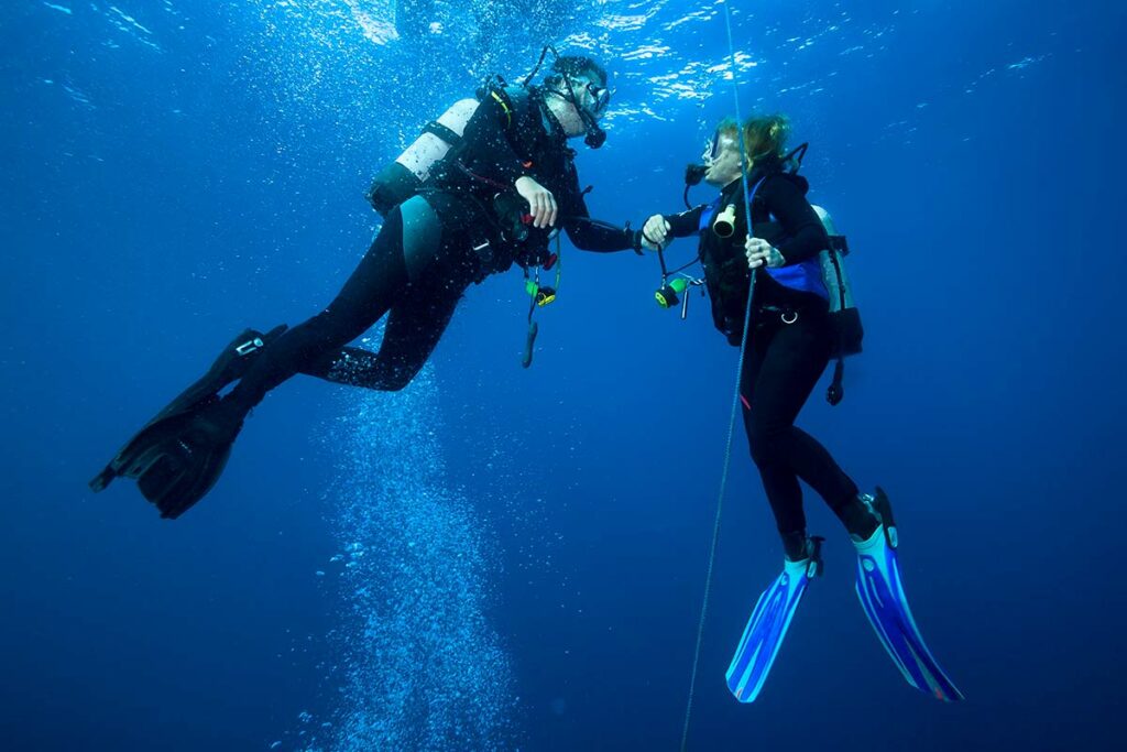 two scuba divers performing safety stop while diving underwater