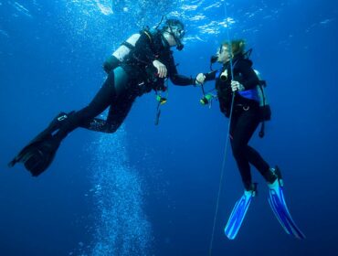 two scuba divers performing safety stop while diving underwater