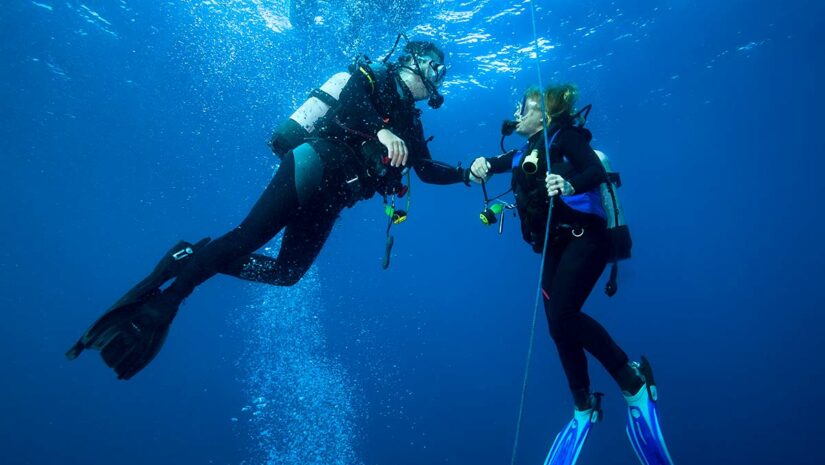two scuba divers performing safety stop while diving underwater